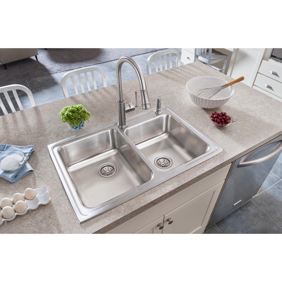Stainless steel drop-in sink with two unequal bowls and single faucet hole, installed in kitchen counter.