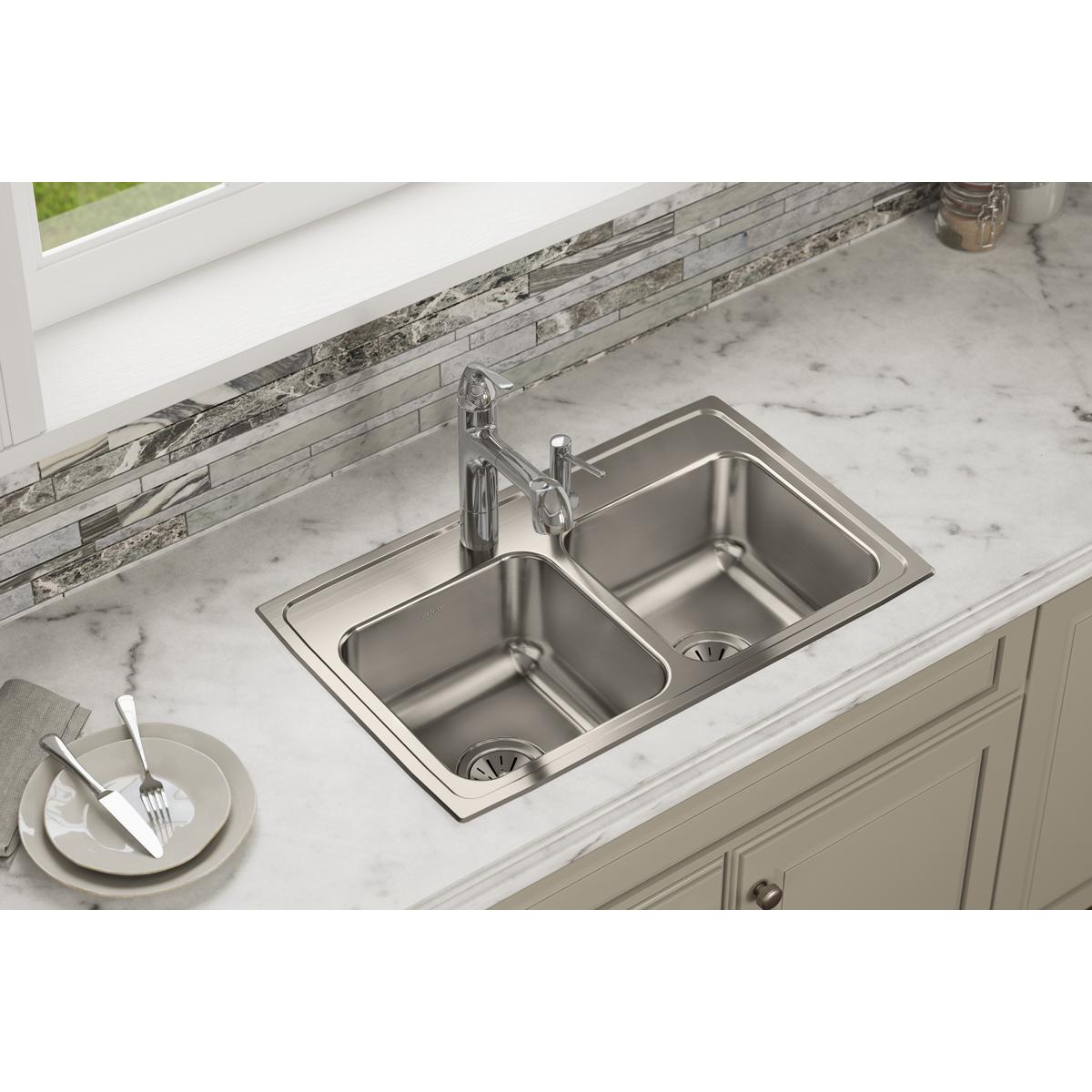 Stainless steel drop-in sink with two equal rectangular bowls and chrome faucet installed in marble countertop.