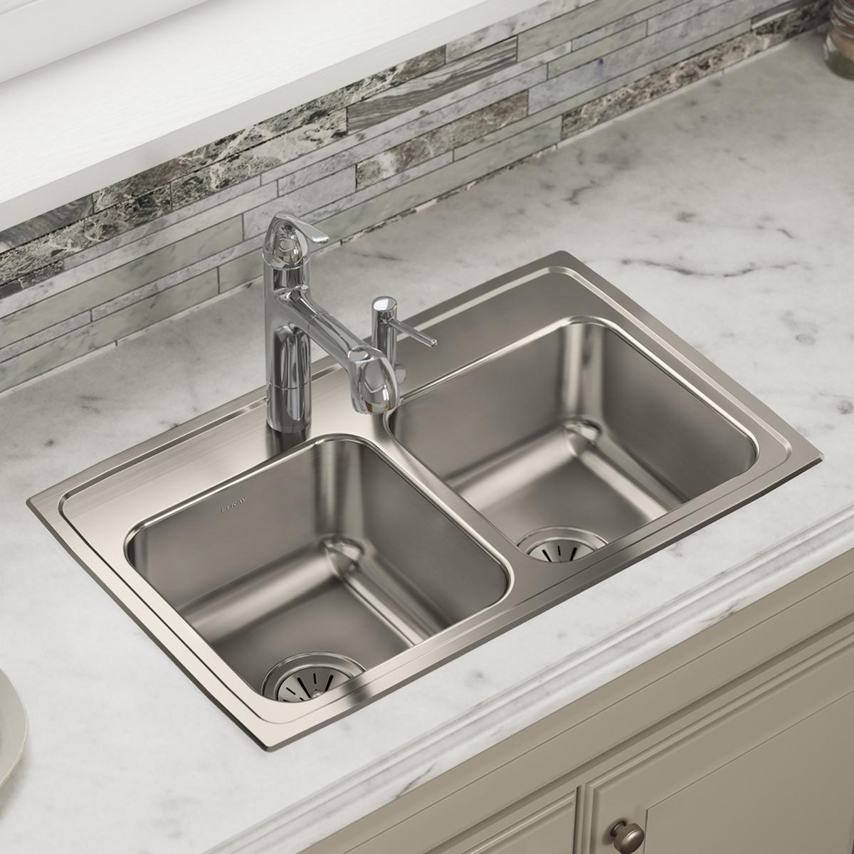 Brushed stainless steel double bowl drop-in sink with chrome faucet installed in marble countertop.