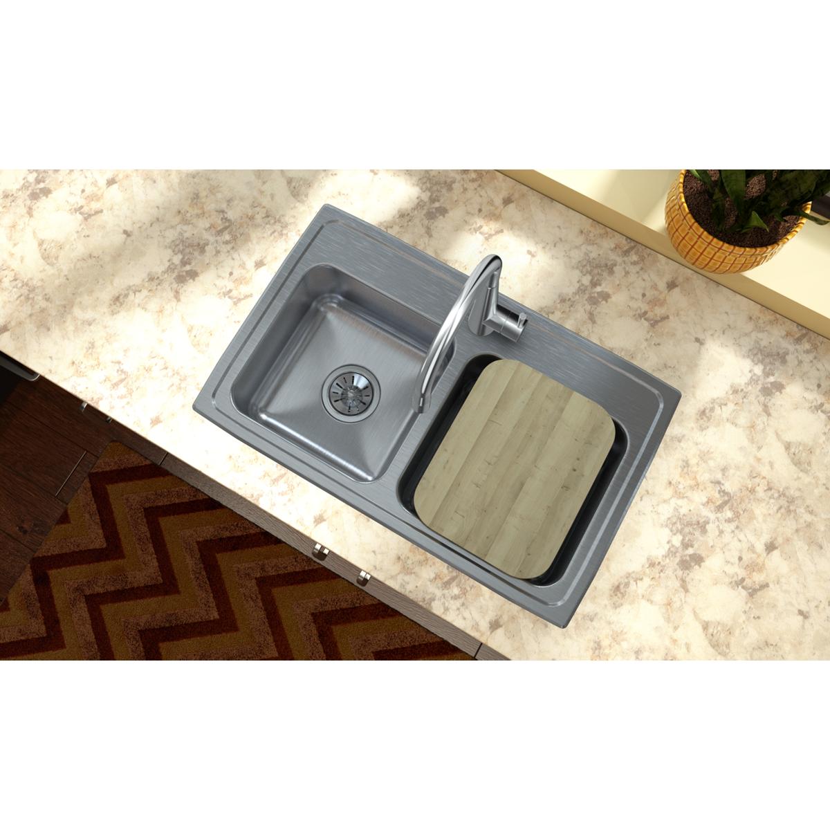 Rectangular hardwood cutting board with light natural finish resting in kitchen sink next to stainless steel basin.
