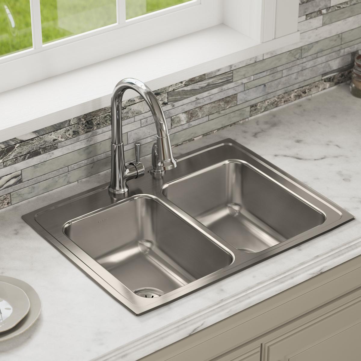 Stainless steel drop-in sink with two equal bowls and three pre-drilled holes, installed in white marble countertop with chro