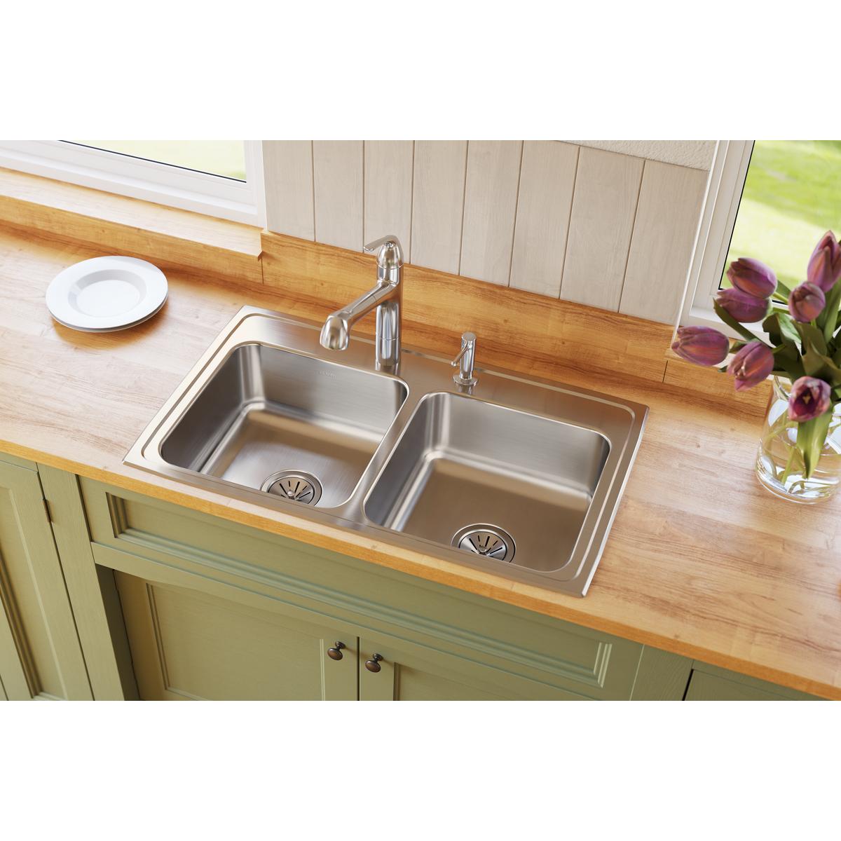 Stainless steel double bowl drop-in sink with two equal-sized basins and chrome faucet installed in wooden countertop.