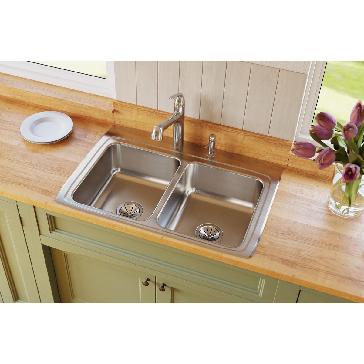 Stainless steel double bowl drop-in sink with equal-sized basins installed in wooden countertop with faucet.