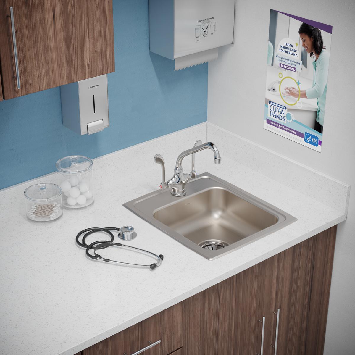 Stainless steel drop-in sink with single bowl and chrome faucet installed in white countertop with wood cabinetry below.