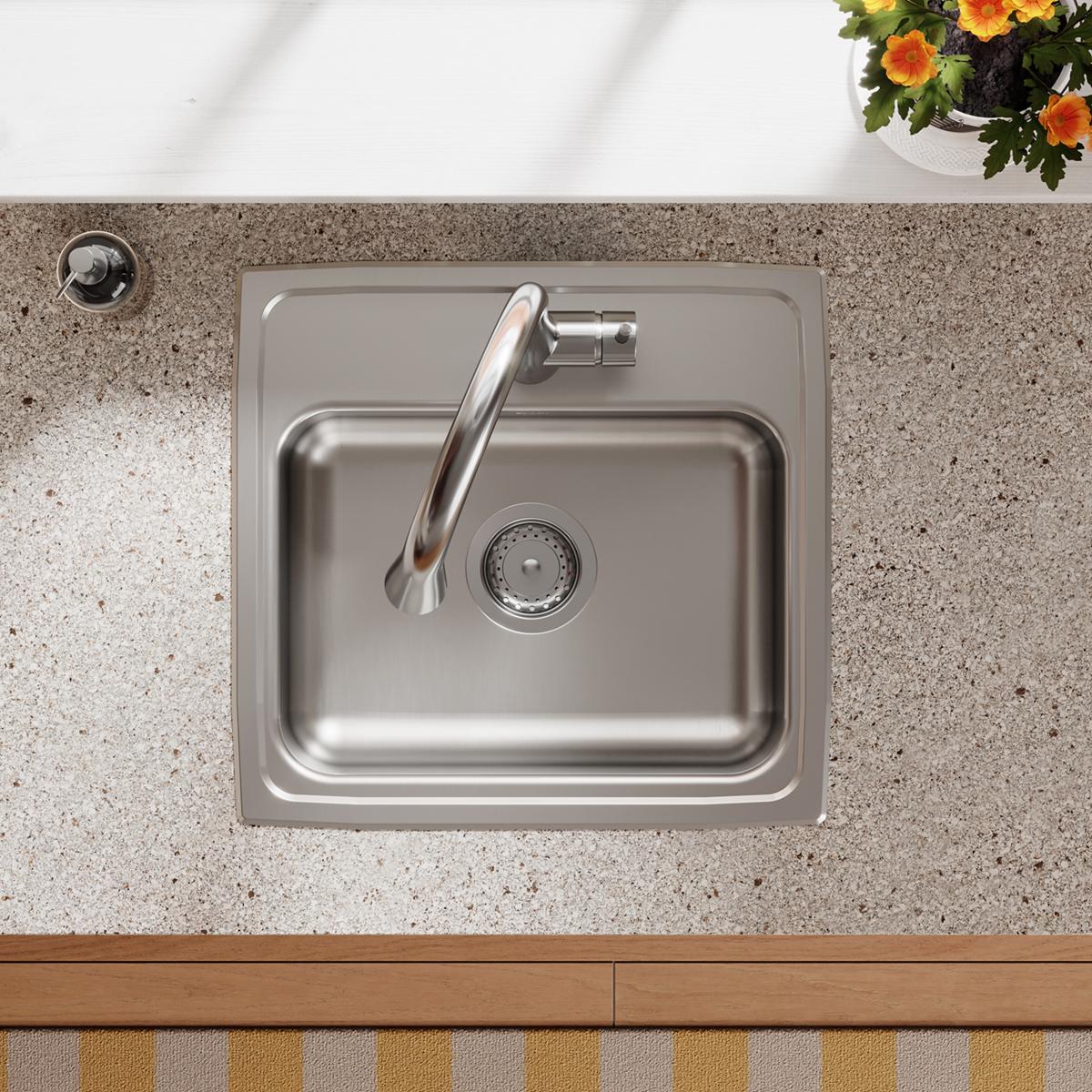 Stainless steel single bowl drop-in sink installed in gray countertop with faucet and drain visible.