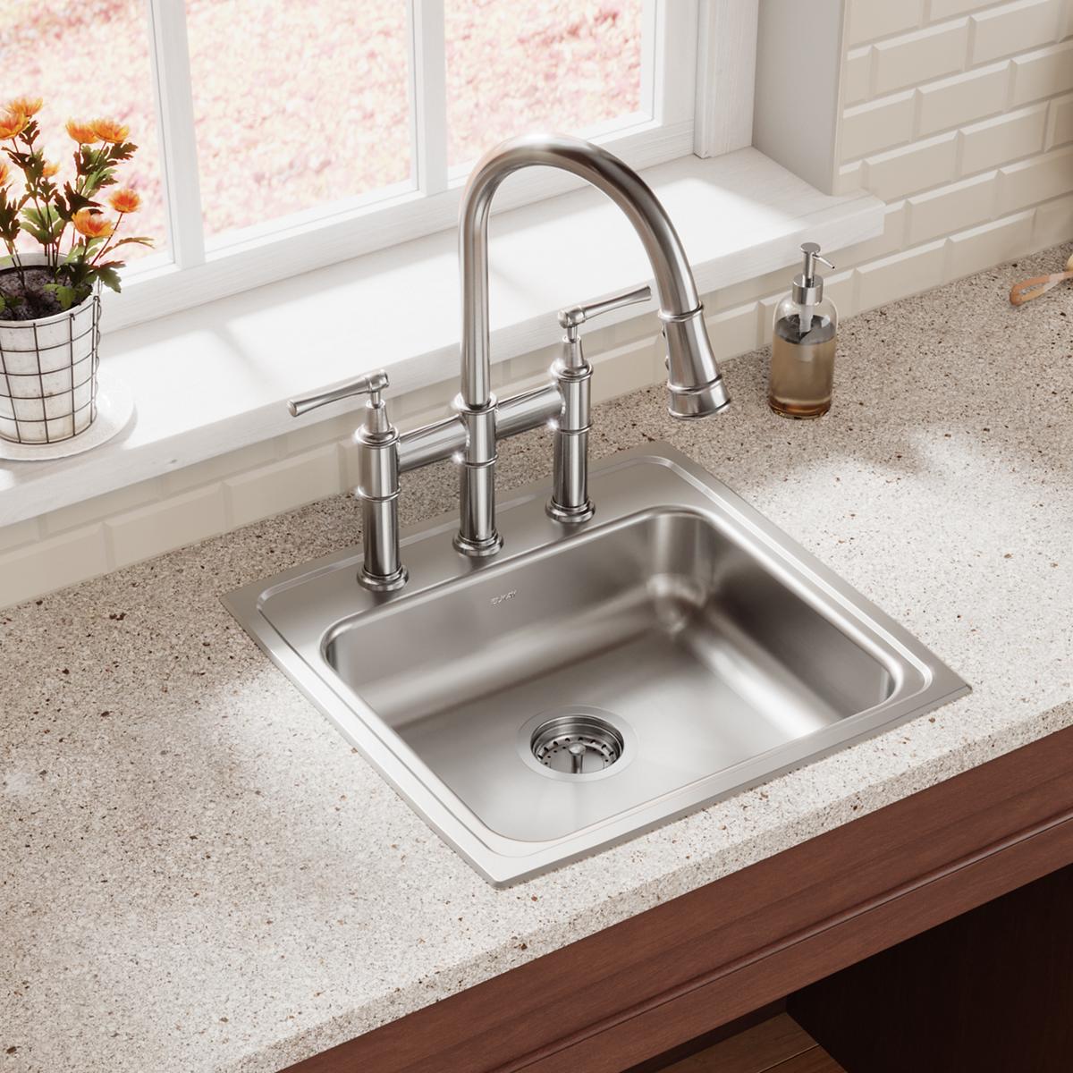Stainless steel single bowl drop-in sink with three faucet holes and chrome faucet installed on countertop.