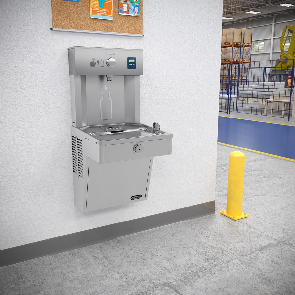 Stainless steel wall-mounted bottle filling station with integrated cooler and single drinking fountain mounted in an industr