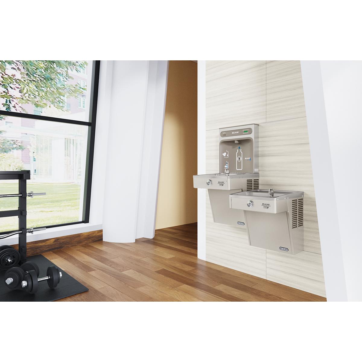 Stainless steel wall-mounted water cooler with two dispensing levels installed in an indoor hallway.