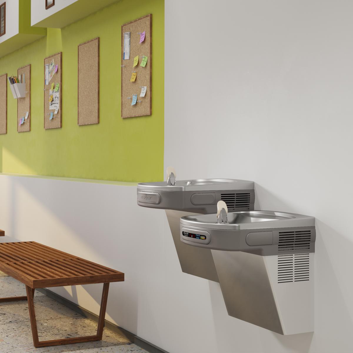 Stainless steel wall-mounted water cooler with two drinking fountains at different heights in an office break room.