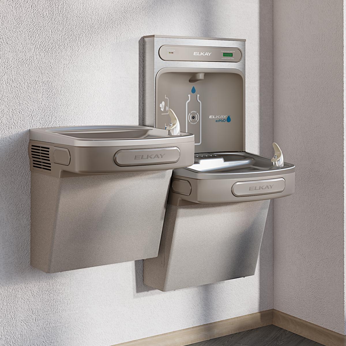 Light gray Elkay water station with upper bottle filling unit and two lower bi-level drinking fountains mounted on wall.