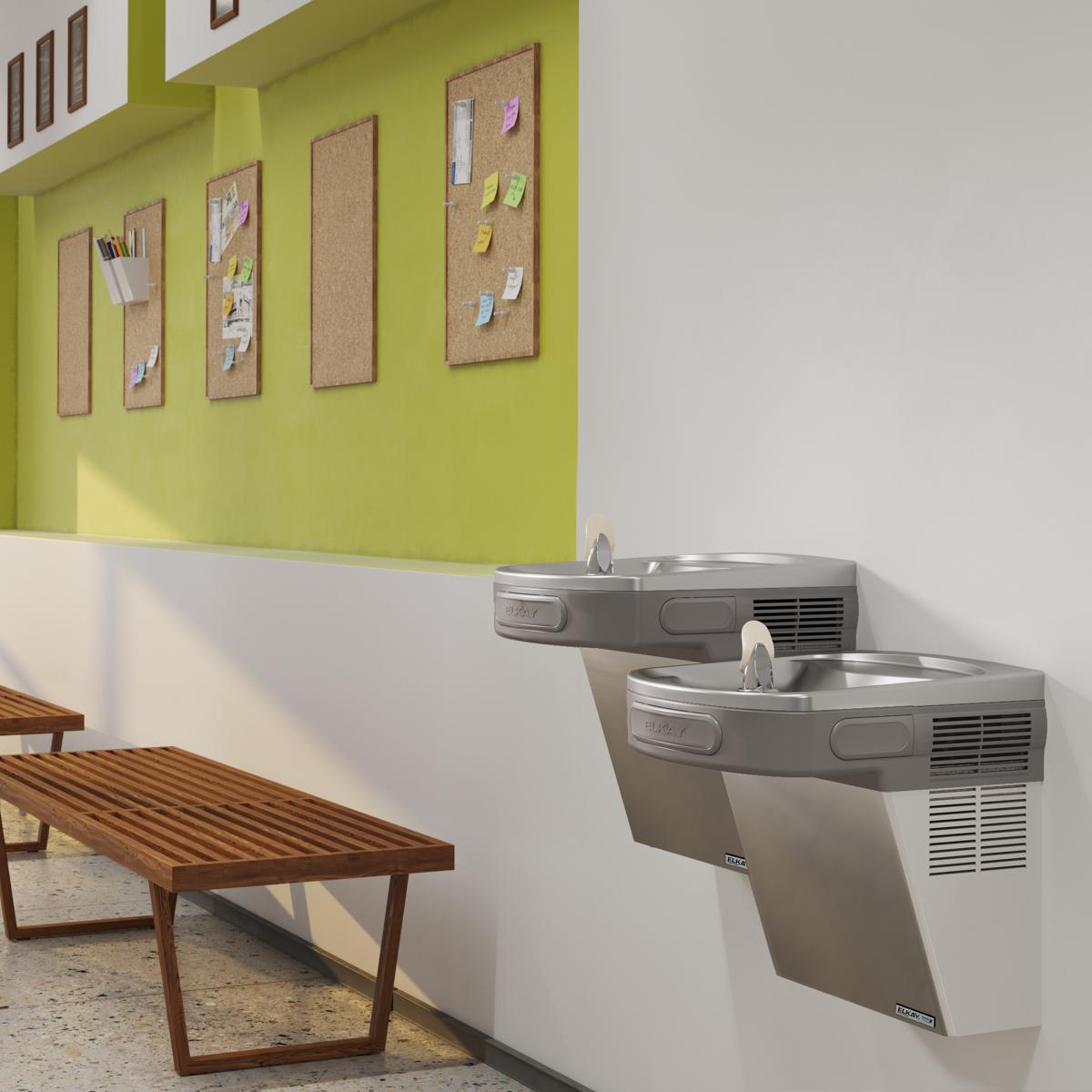 Stainless steel wall-mounted water cooler with two drinking fountains at different heights, installed on a white and yellow w