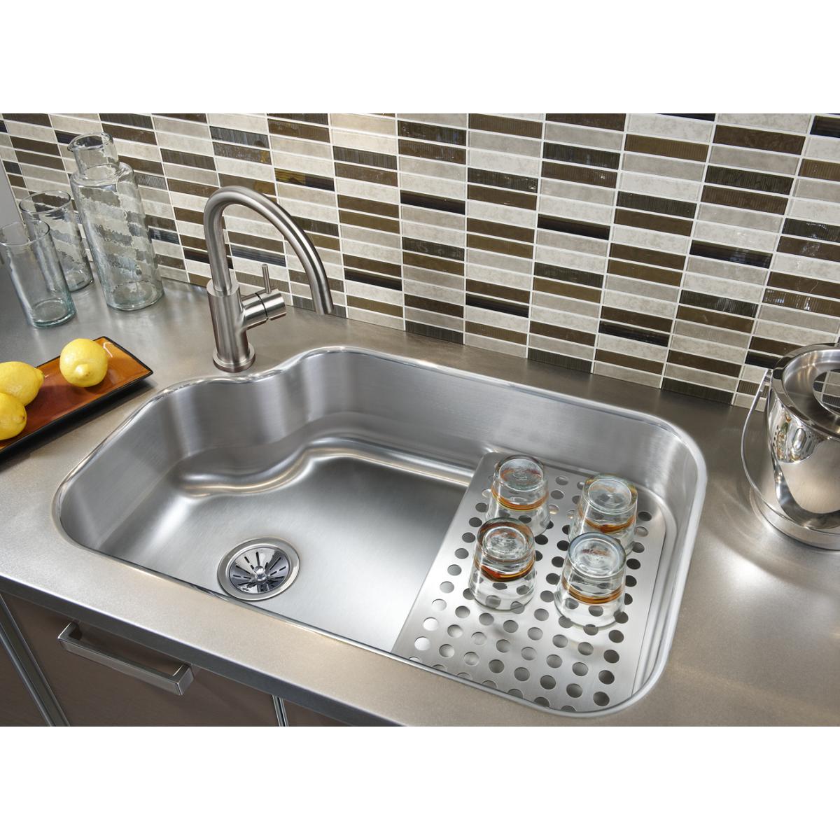 Satin stainless steel single-hole kitchen faucet with curved lever handle mounted above undermount sink basin.