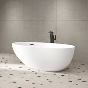 White oval freestanding bathtub with curved sides and black floor-mounted faucet in bathroom setting.