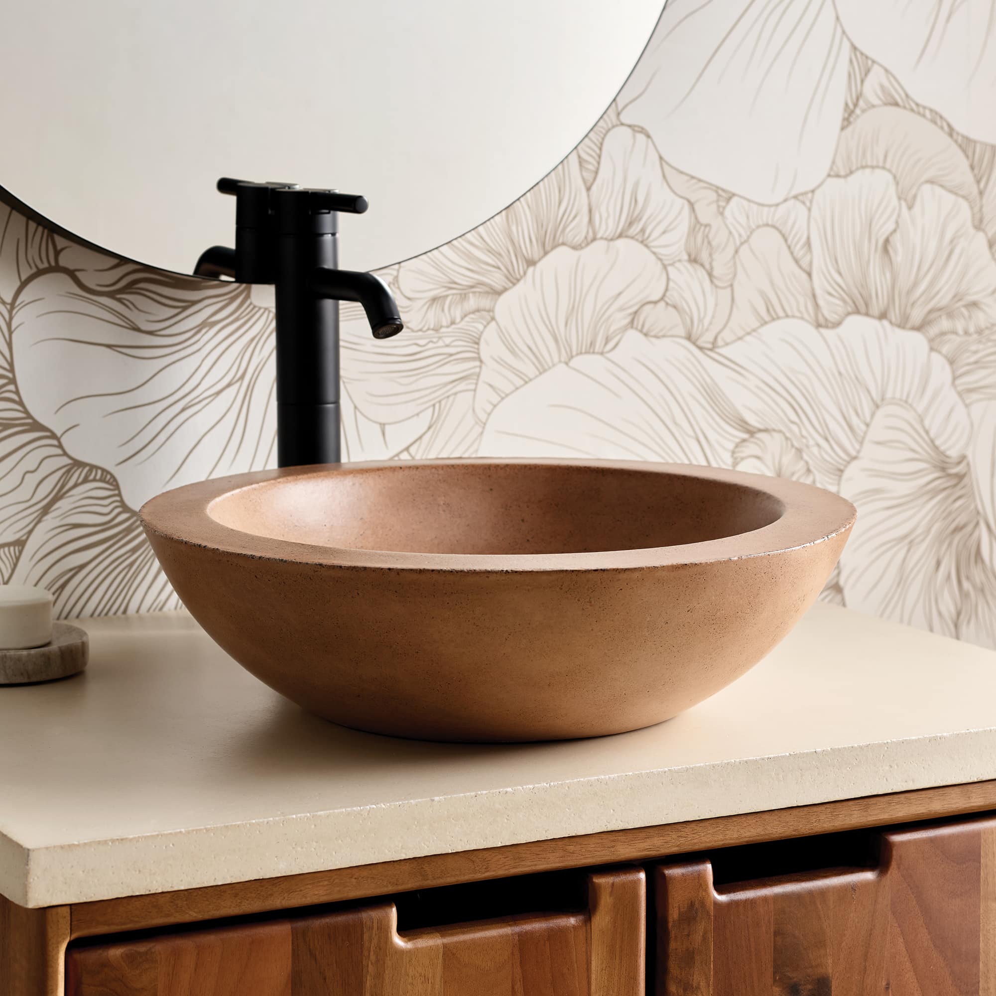 Terracotta-colored round vessel sink with black faucet mounted on cream countertop against patterned backsplash.