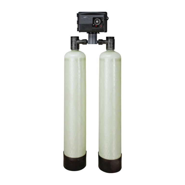 Dual fiberglass water treatment tanks with black control valve head and inlet/outlet ports mounted on top.