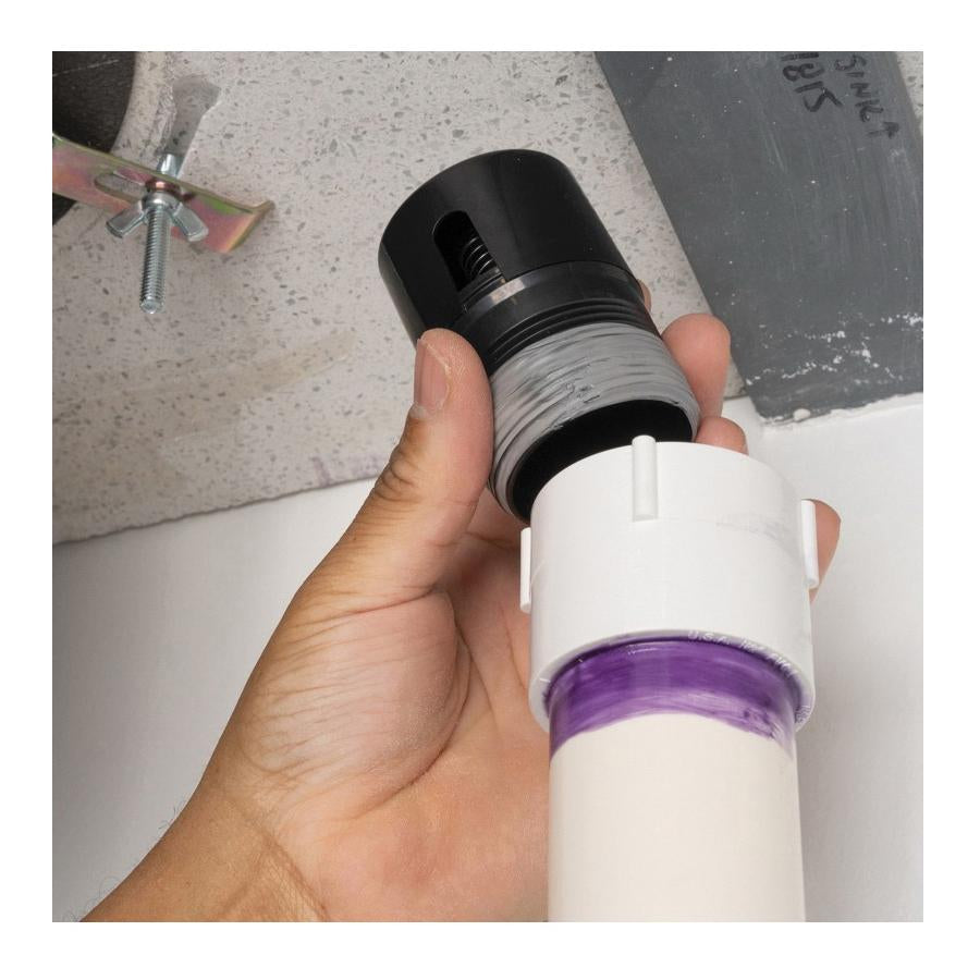 Black and white ABS inline vent with threaded connections and purple seal band, held in hand.