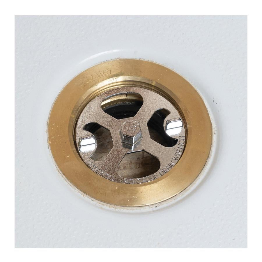 Brass and plastic shower drain wrench with circular brass rim and metal center featuring multiple socket openings and adjustm