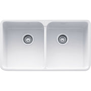 White fireclay apron front double bowl kitchen sink with chrome drain strainers.