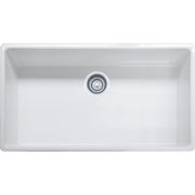 White fireclay farmhouse sink with single bowl and apron front, shown from above with chrome drain fitting.
