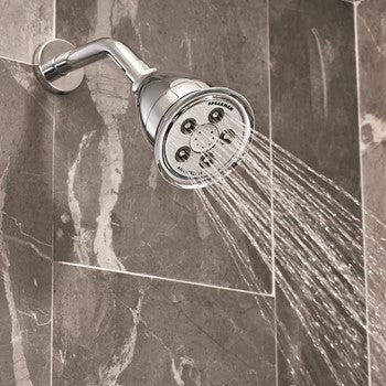 Polished chrome shower head with multiple spray holes mounted on wall with curved arm.