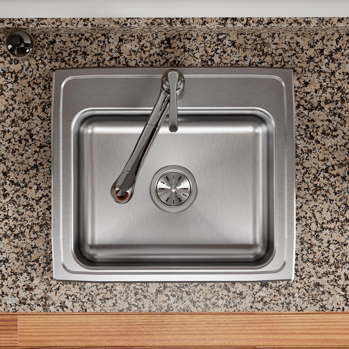 Stainless steel drop-in sink with single bowl, drain strainer, and black faucet installed in speckled granite countertop.