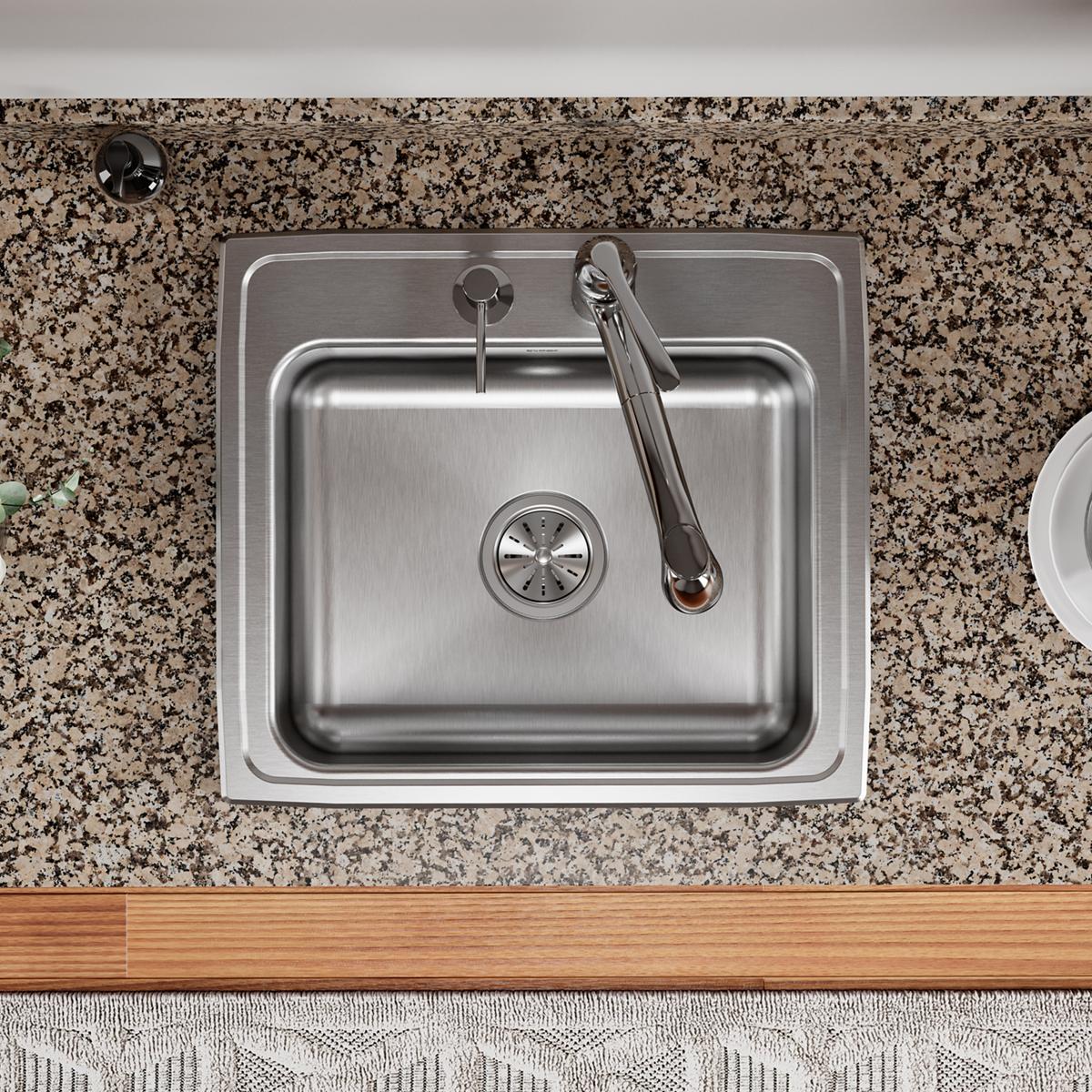 Stainless steel drop-in sink with single bowl, two mounting holes, and chrome faucet on speckled granite countertop.