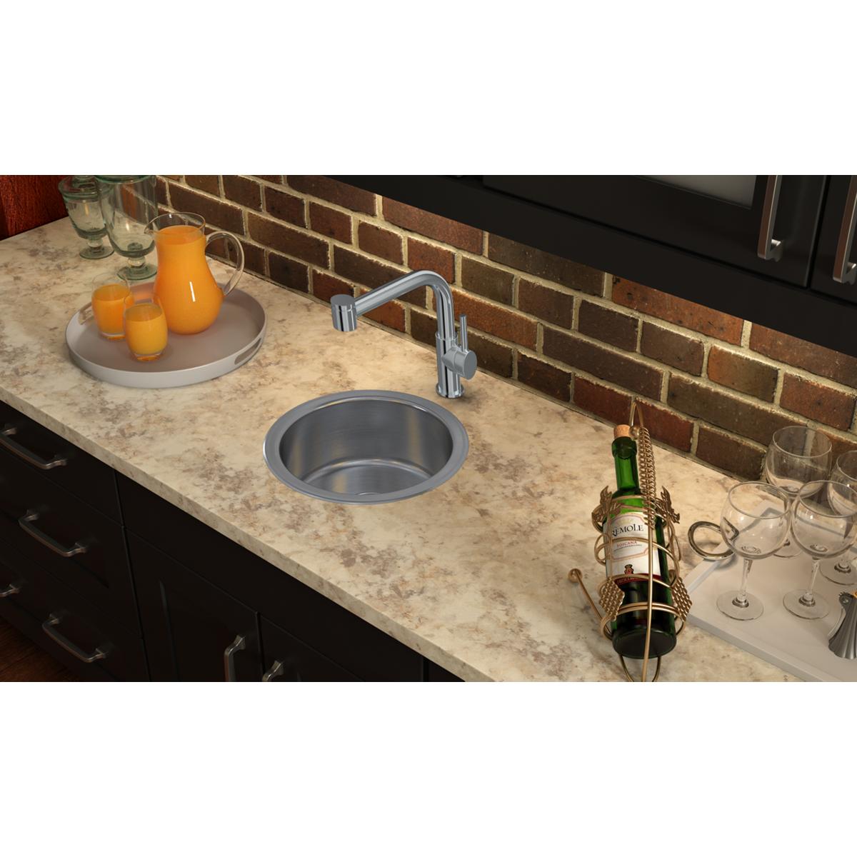 Stainless steel round drop-in bar sink installed in marble countertop with chrome faucet.