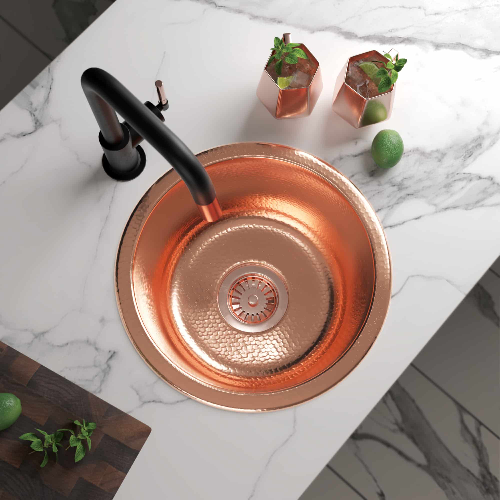 Polished copper round sink with hammered interior texture and black faucet on marble countertop.