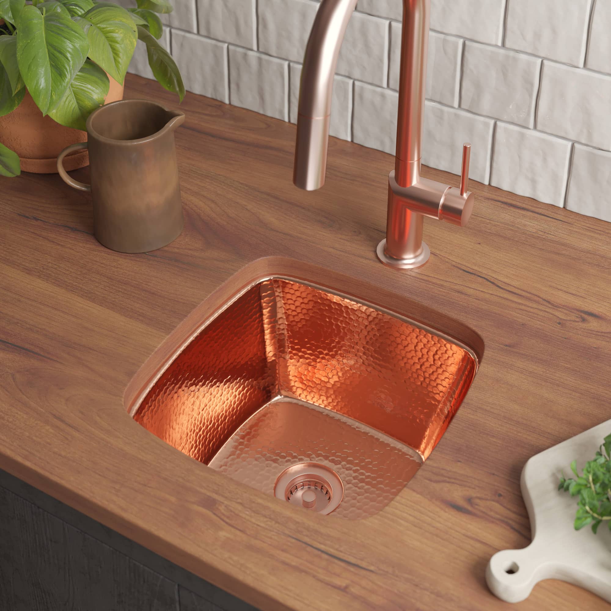 Polished copper square sink with hammered texture mounted in wood countertop next to faucet.