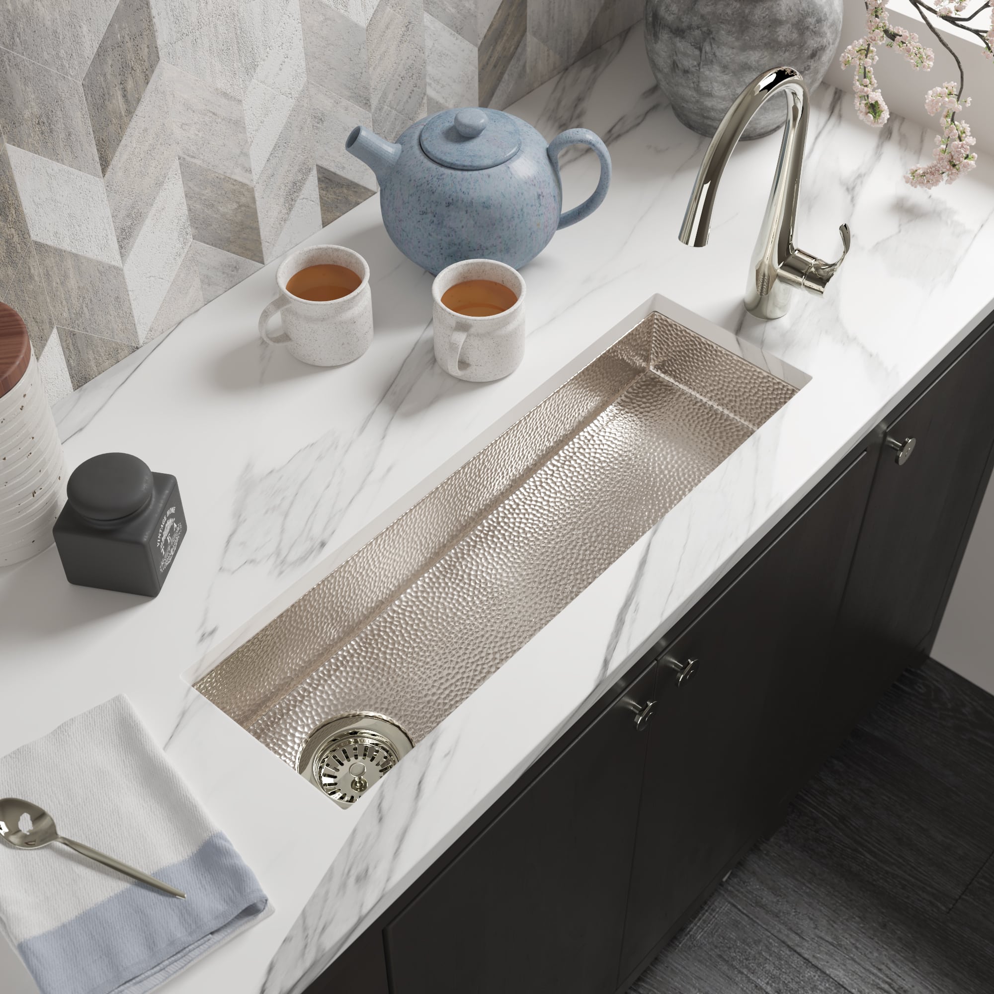 Polished nickel bathroom sink with hammered texture basin mounted in marble countertop.