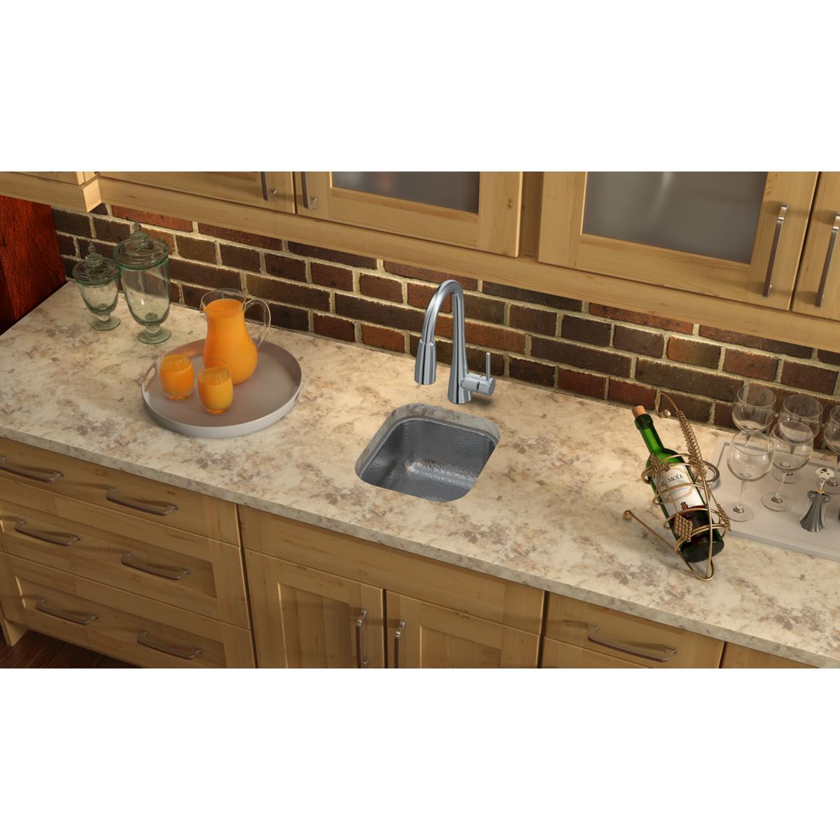 Stainless steel undermount bar sink installed in marble countertop with chrome faucet.
