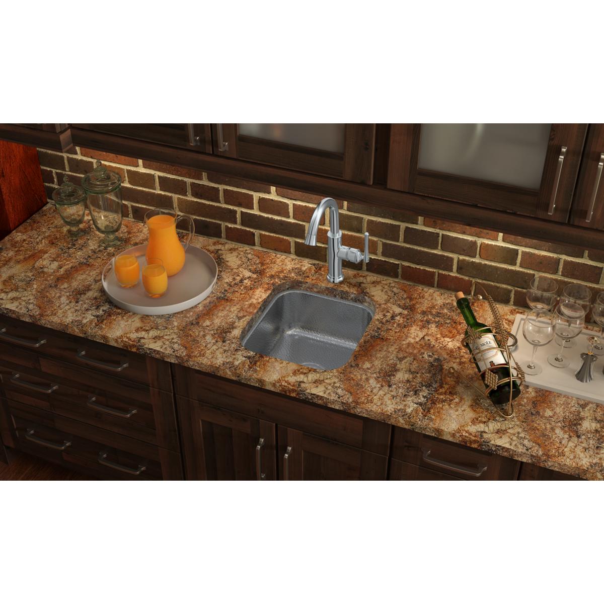 Stainless steel single bowl undermount sink installed in granite countertop with chrome faucet.