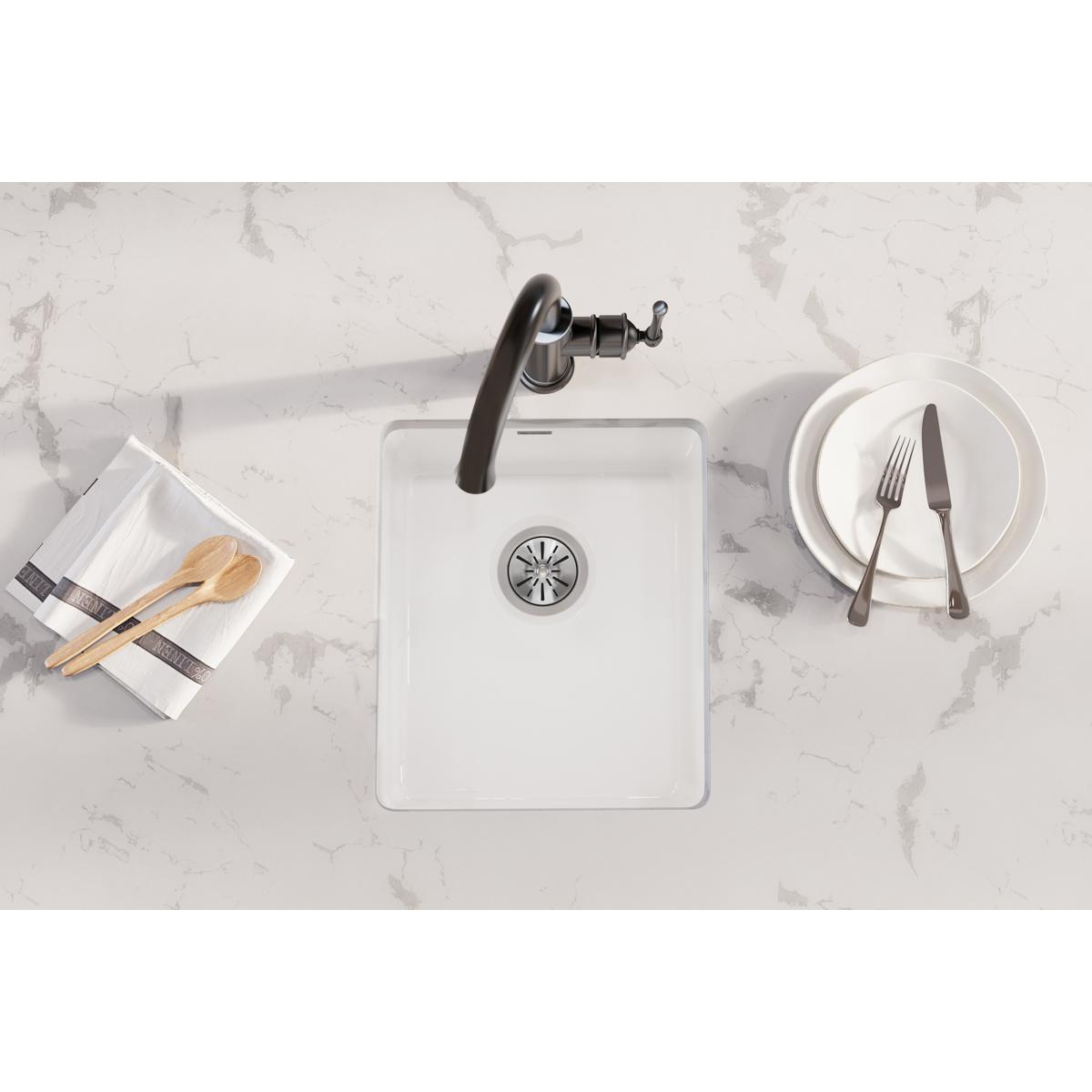 White fireclay undermount bar sink with single bowl and drain, shown from above on marble countertop.