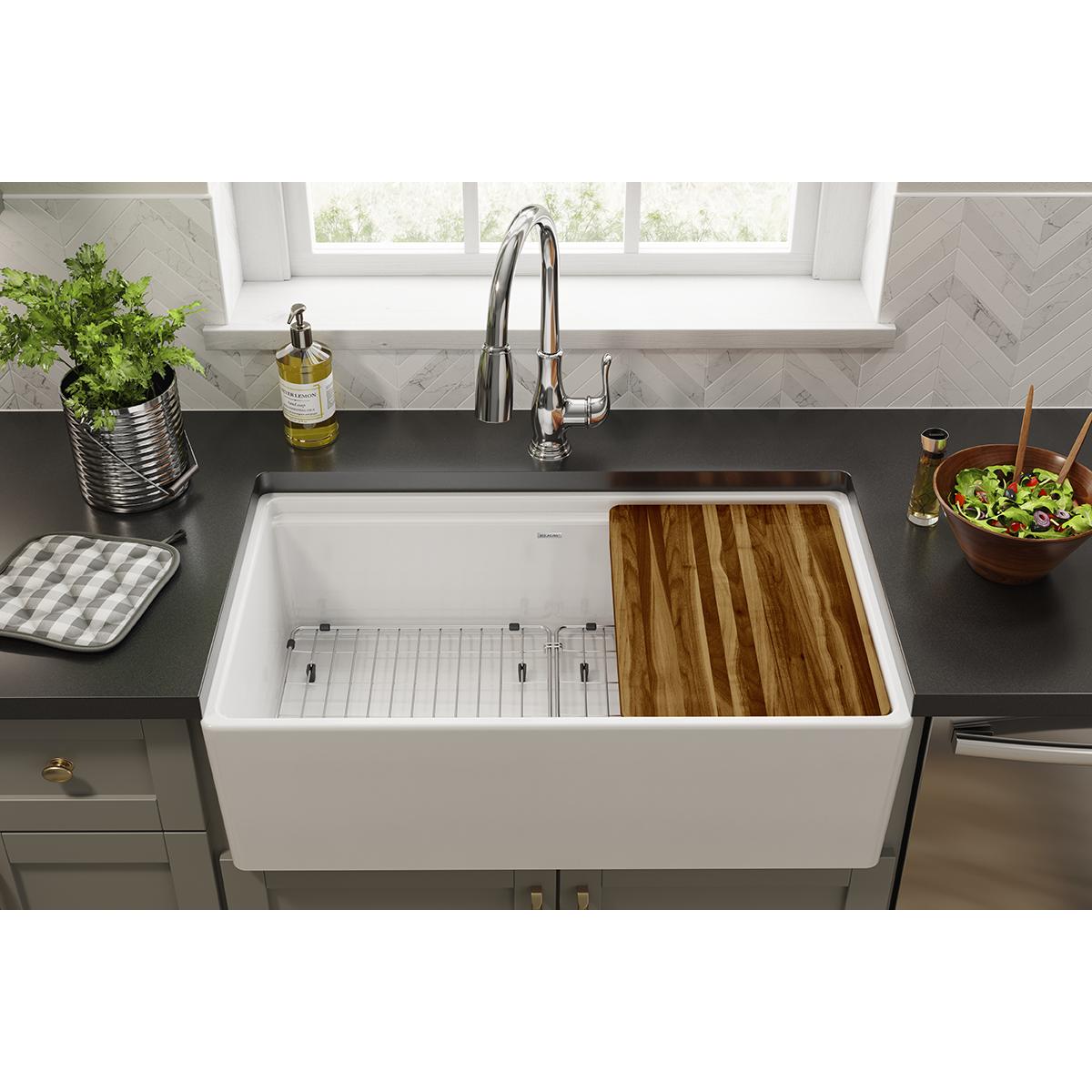 Stainless steel bottom grid with vertical slats positioned inside a white farmhouse sink basin.