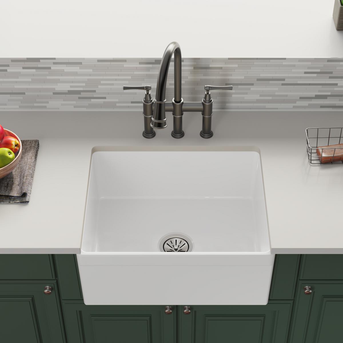 White fireclay single-bowl farmhouse sink with apron front and stainless steel faucet installed in countertop.