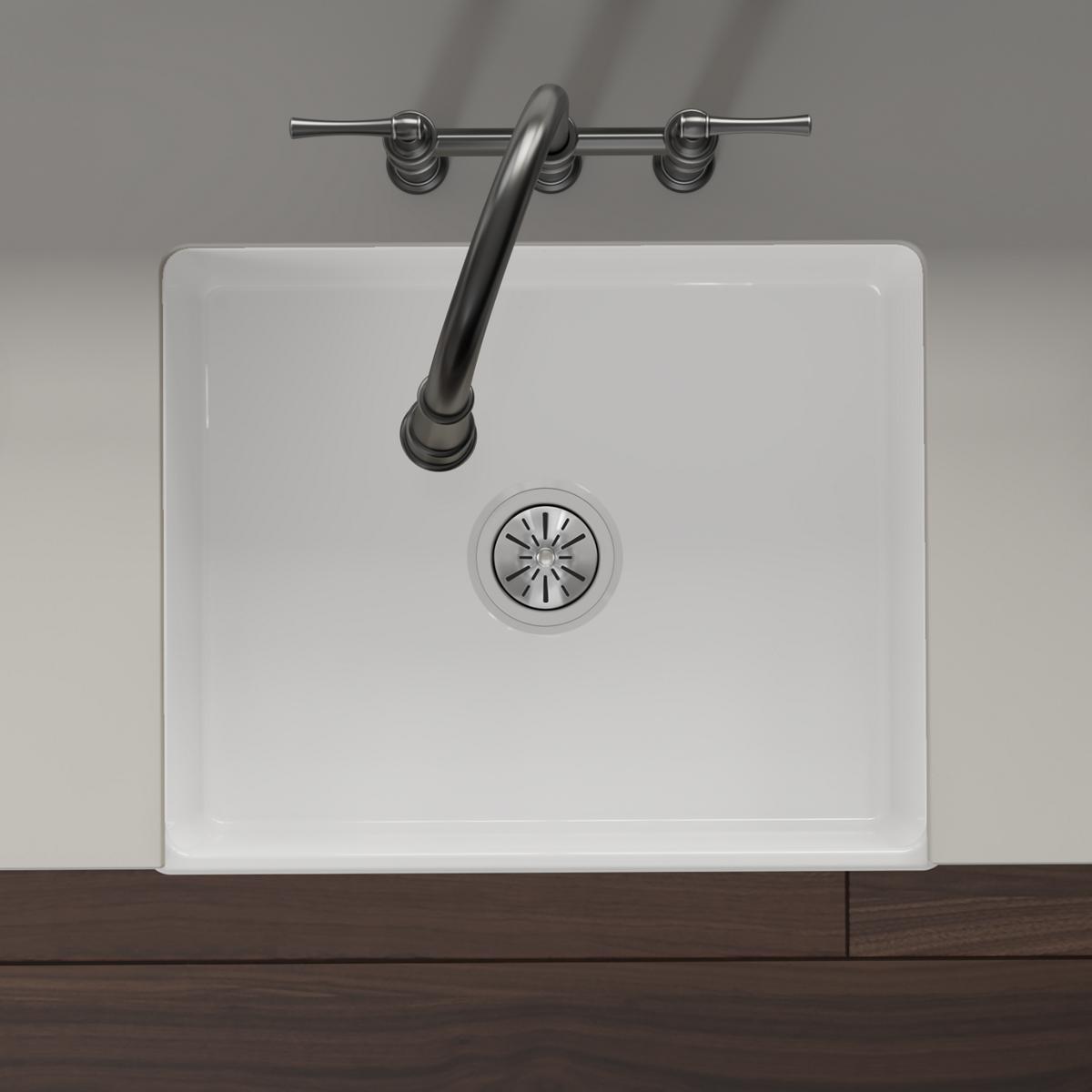 White fireclay farmhouse sink with single bowl, rounded corners, and chrome faucet with curved spout mounted above.