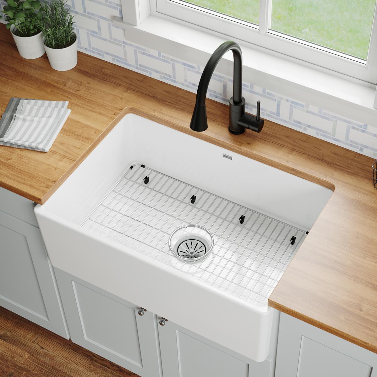 Stainless steel bottom grid with vertical slat pattern inside white farmhouse sink basin.