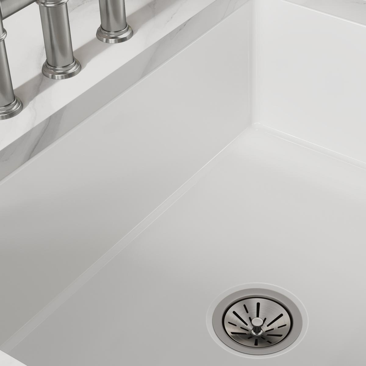 White fireclay farmhouse sink with single bowl, drain, and stainless steel faucet visible at rim.