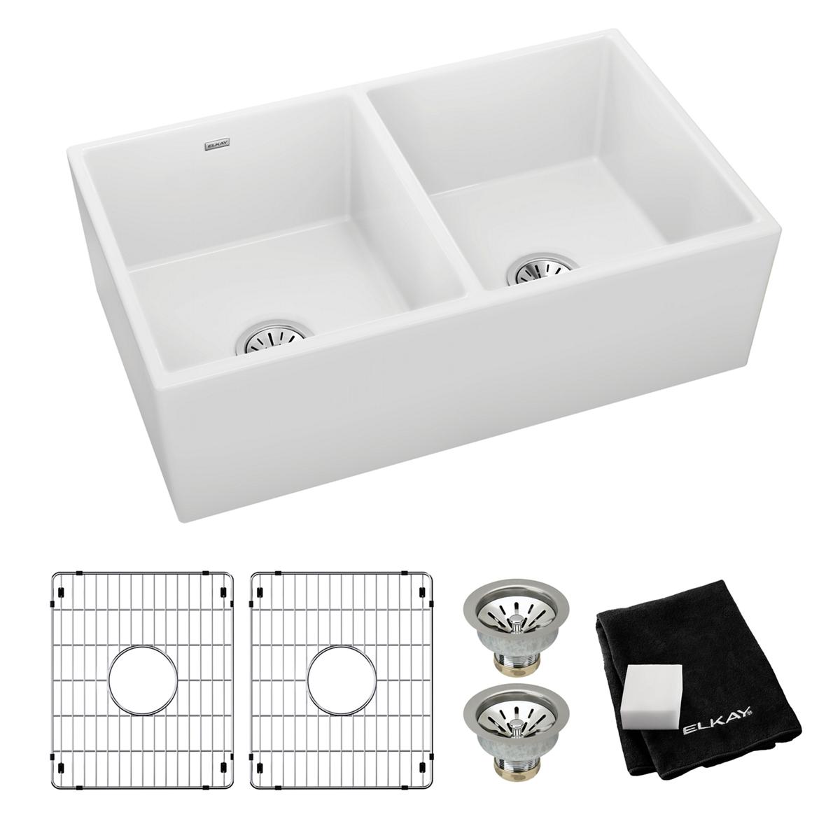 White fireclay farmhouse sink with two equal bowls, including grid strainers, drain baskets, and cloth.