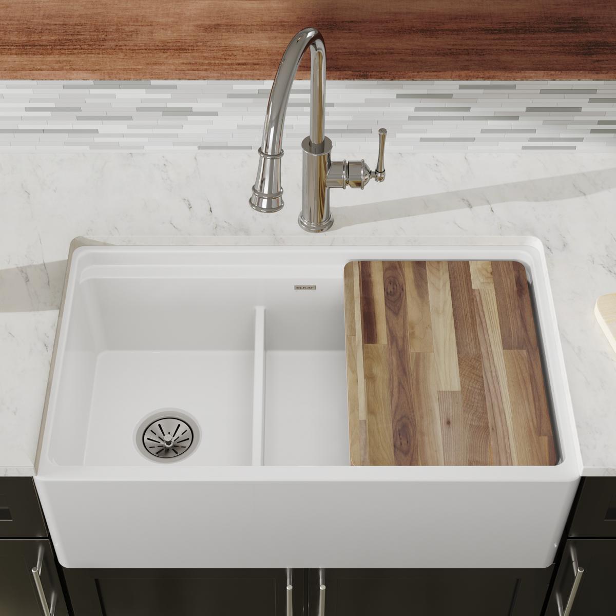 White fireclay farmhouse sink with two bowls divided by a center partition, featuring a drain on the left and a wood cutting 