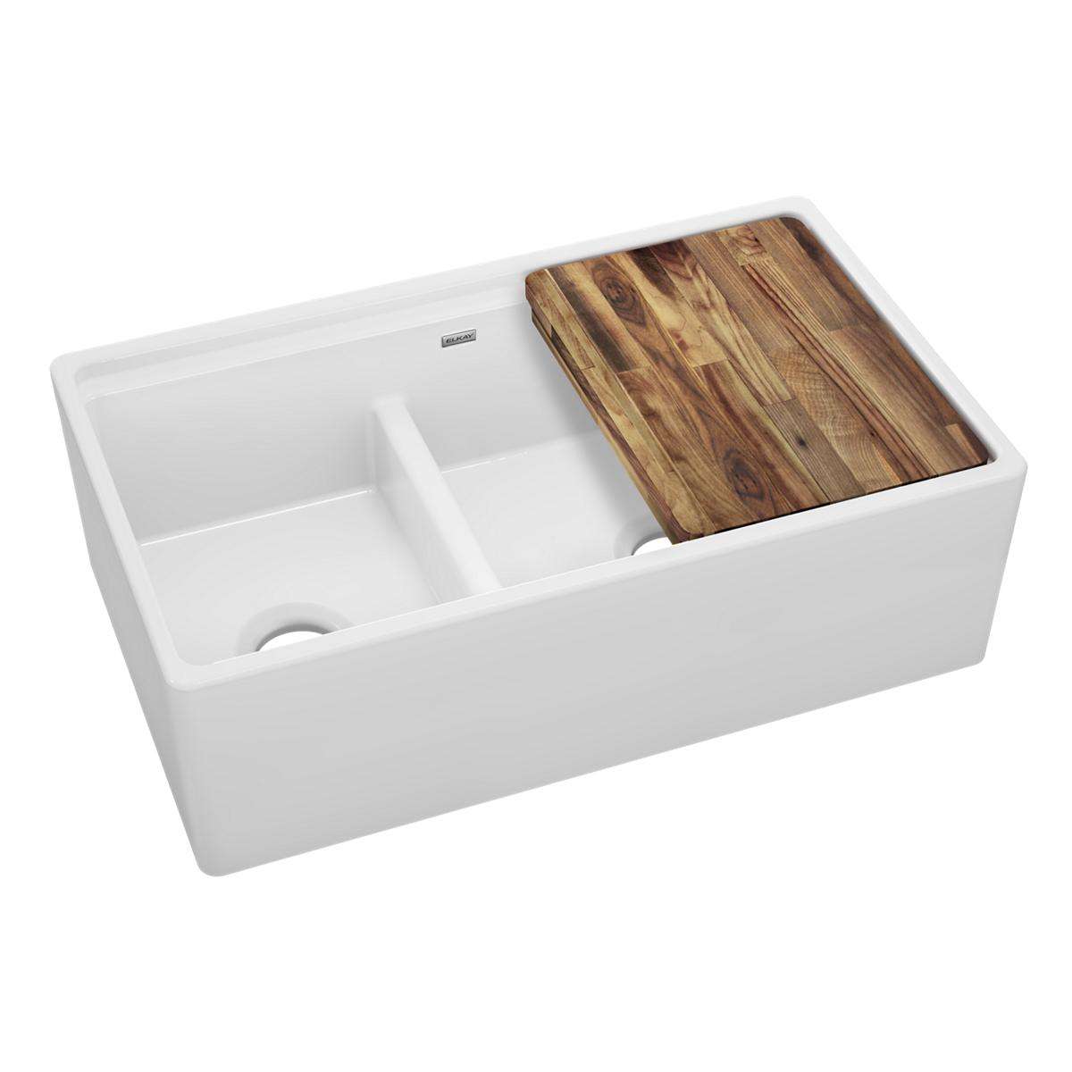 White fireclay double bowl farmhouse sink with unequal basins, divider, and wood cutting board accessory.