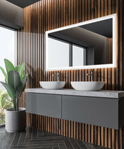 Rectangular lighted mirror with white LED border mounted above gray vanity with two white vessel sinks and wood slat wall bac