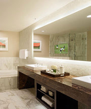 Illuminated bathroom mirror with integrated 15" TV displaying soccer match, mounted above dark vanity in marble bathroom.