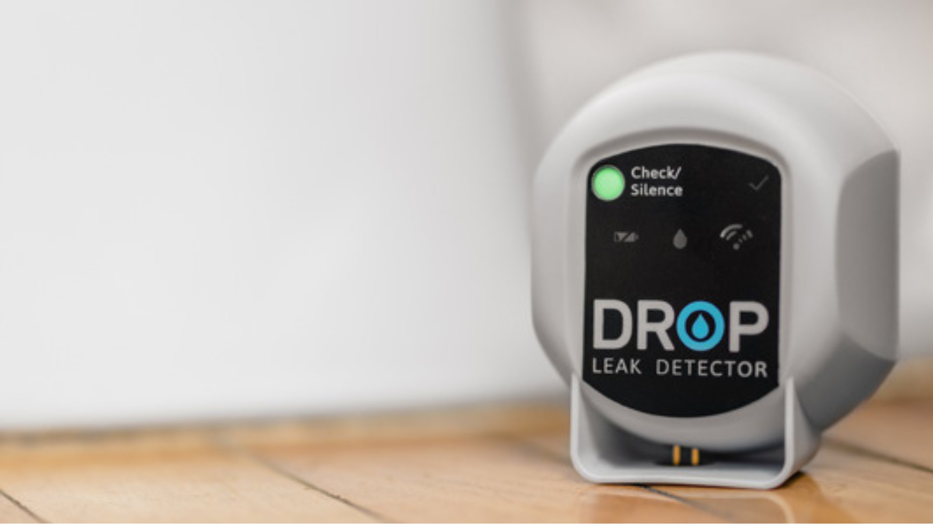 DROP leak detector on a wooden floor with a white wall background