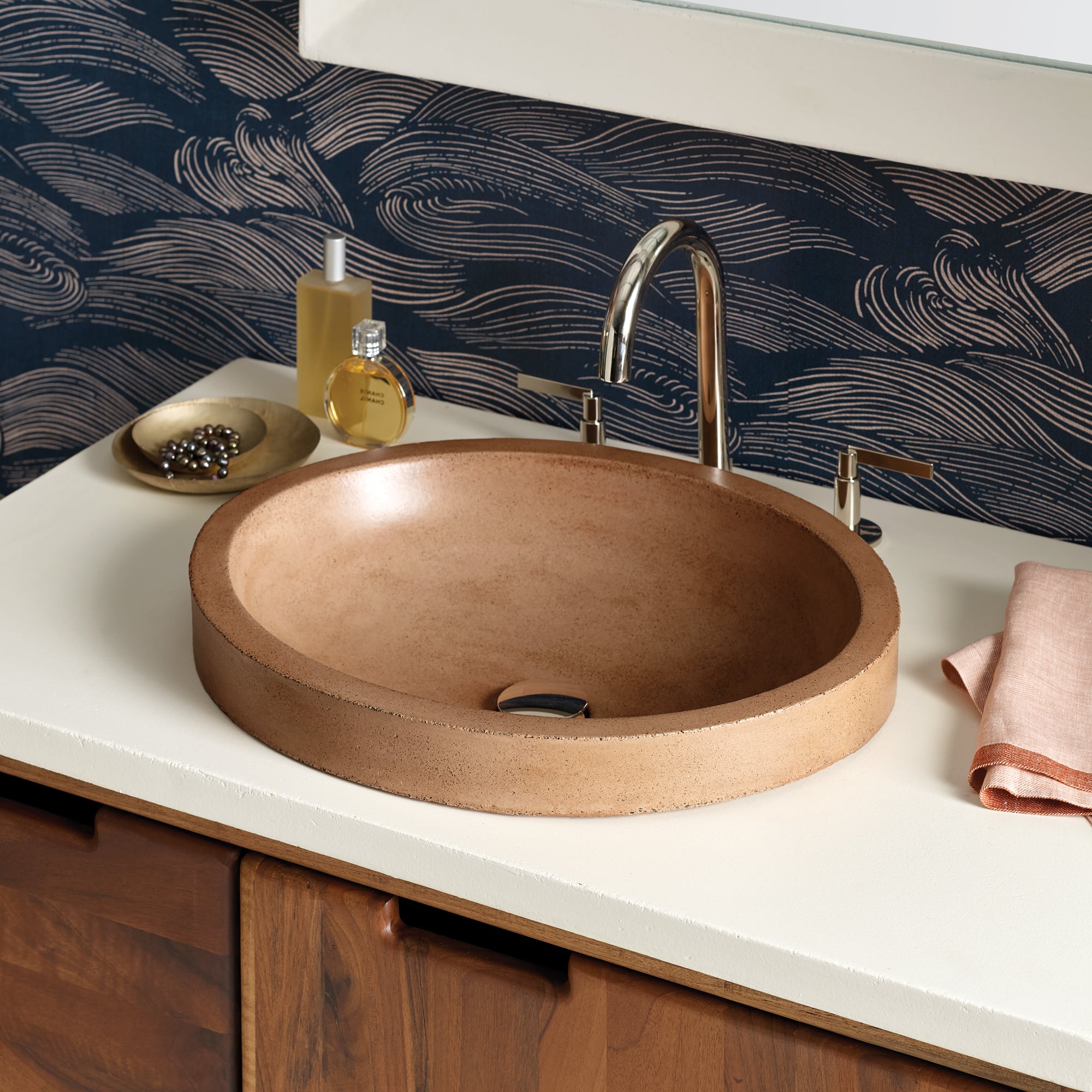 Terracotta round vessel sink with brushed nickel faucet installed on white countertop with patterned backsplash.