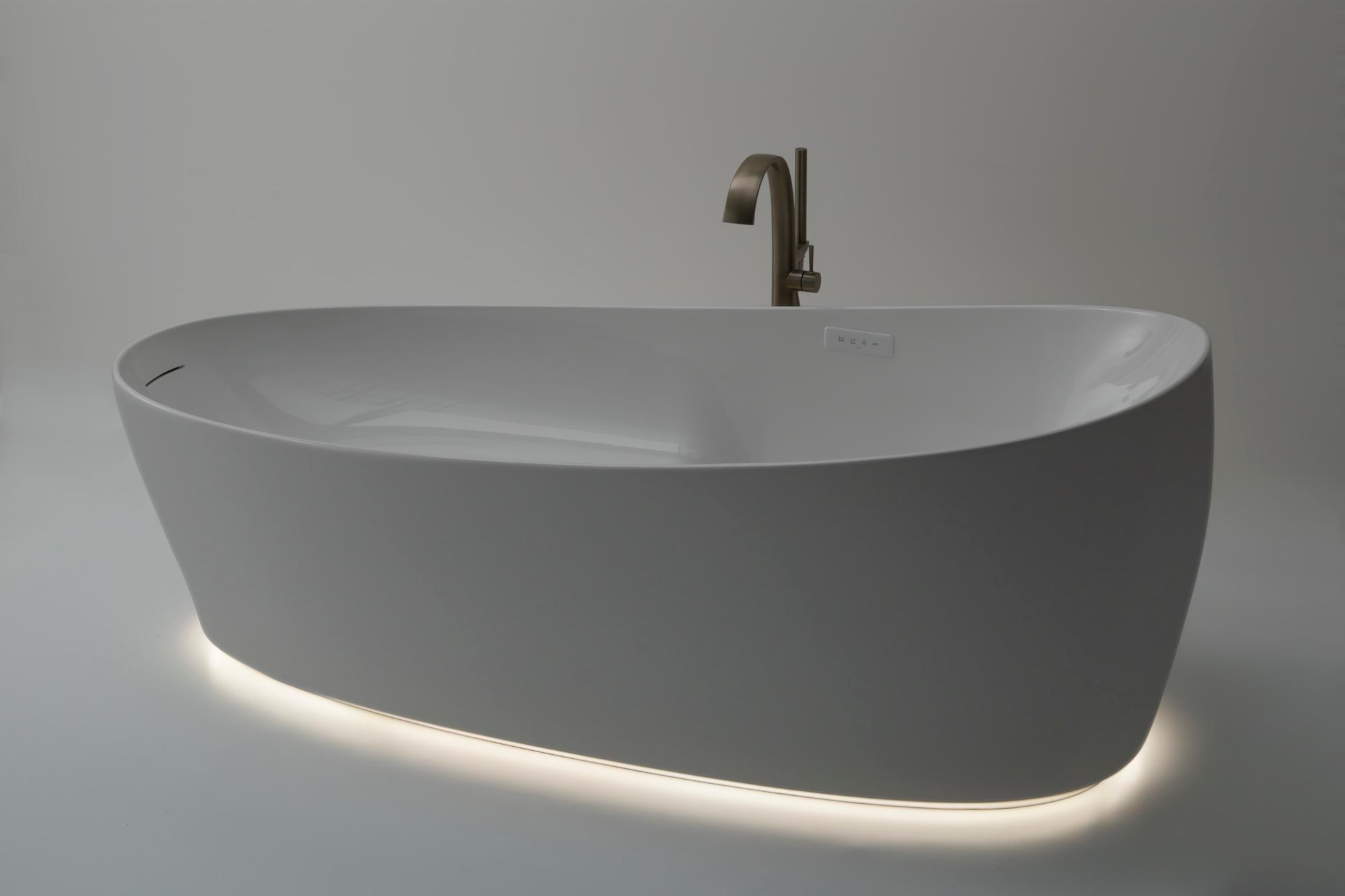 White freestanding soaking tub with curved sides, deck-mounted filler faucet, and integrated lighting along the base.