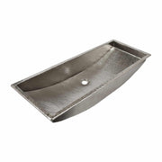 Polished nickel trough sink with hammered interior surface and single drain hole.