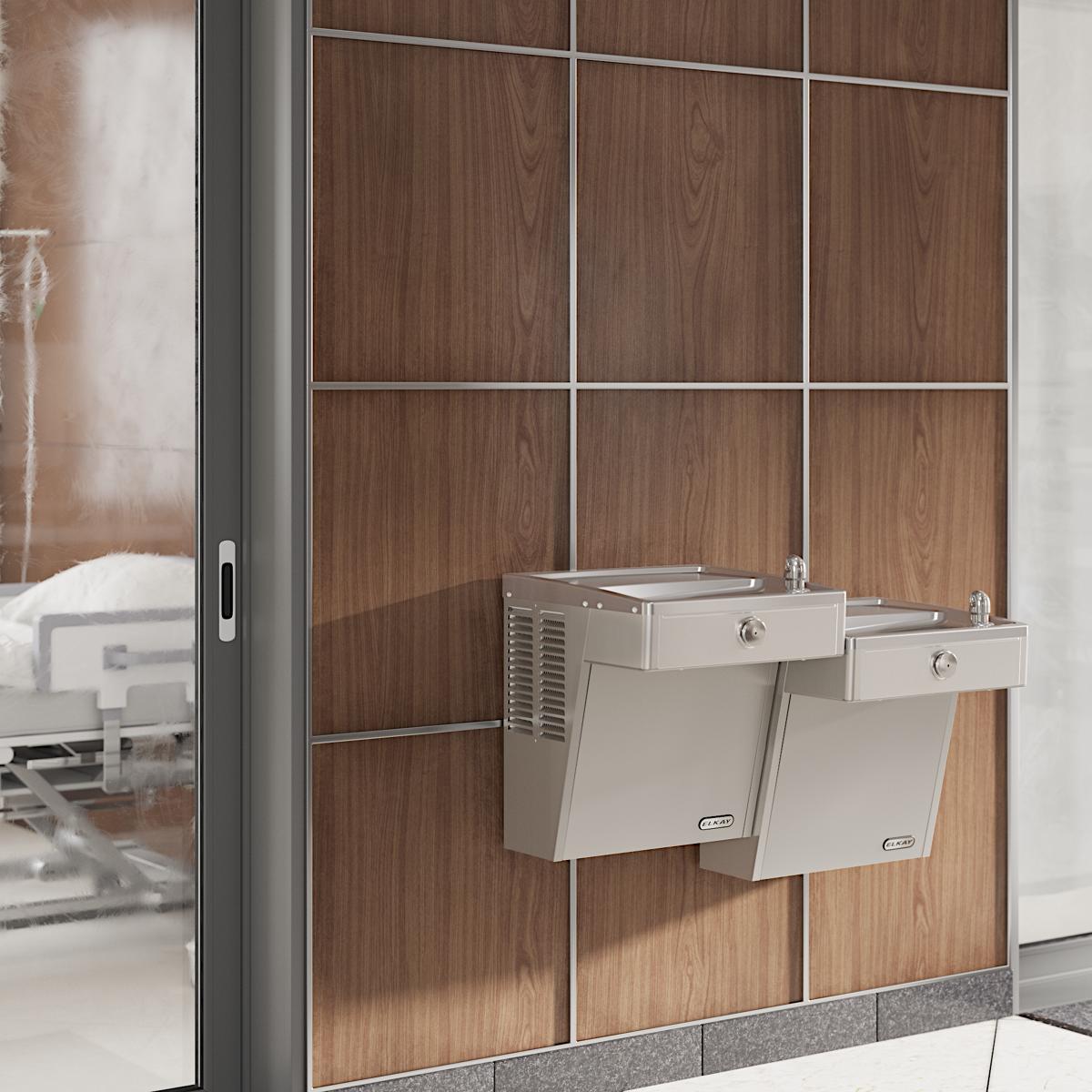 Stainless steel wall-mounted bi-level water cooler with two drinking fountains at different heights mounted on brown tile wal