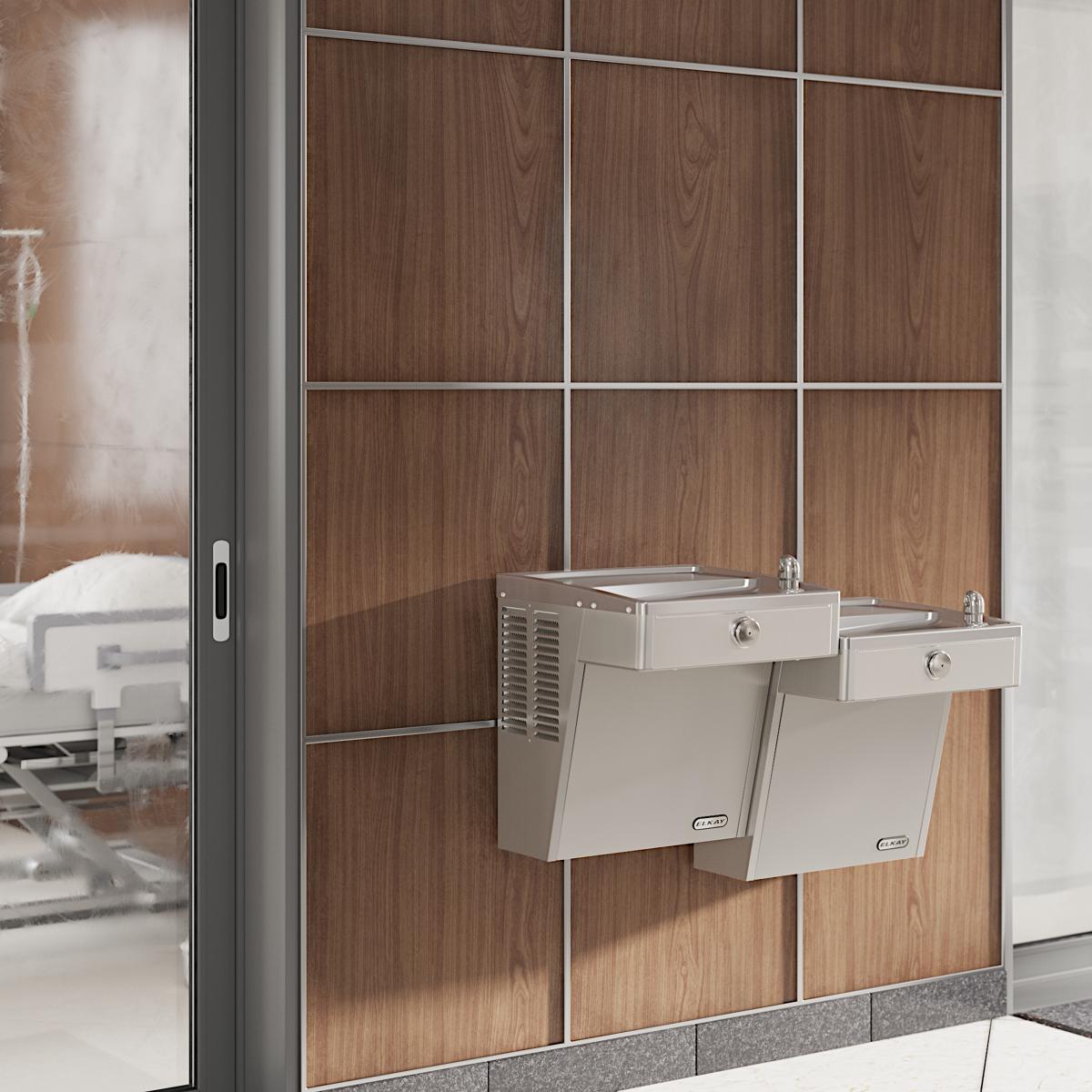Stainless steel wall-mounted water cooler with two bi-level drinking fountains mounted on wood paneling.