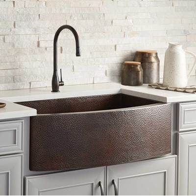 Antique copper farmhouse sink with hammered texture, black pull-down faucet, and white subway tile backsplash.